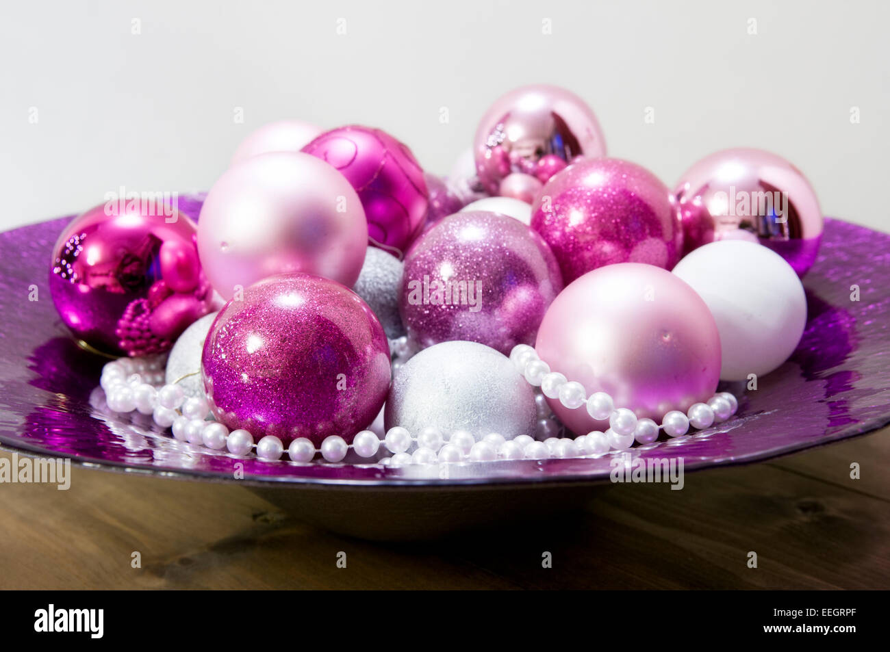 Festive purple bowl filled with Christmas baubles and beads Stock Photo
