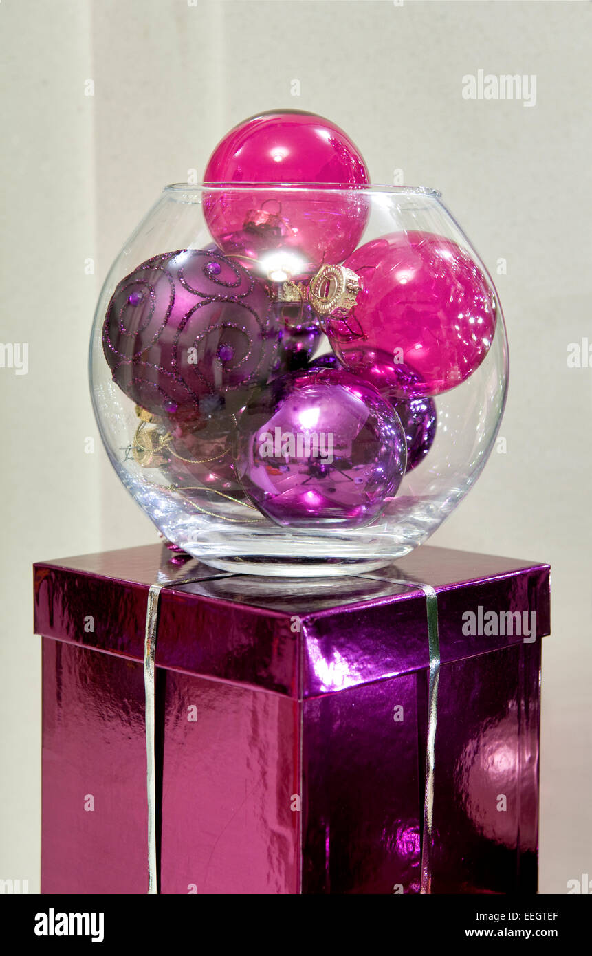 Decorative glass bowl filled with pink baubles on pink box Stock Photo