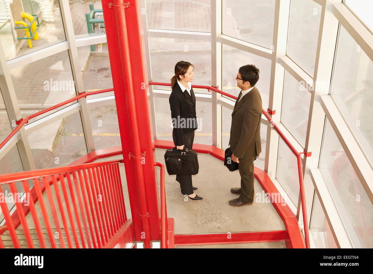 Business couple talking at the bottom of stairs Stock Photo