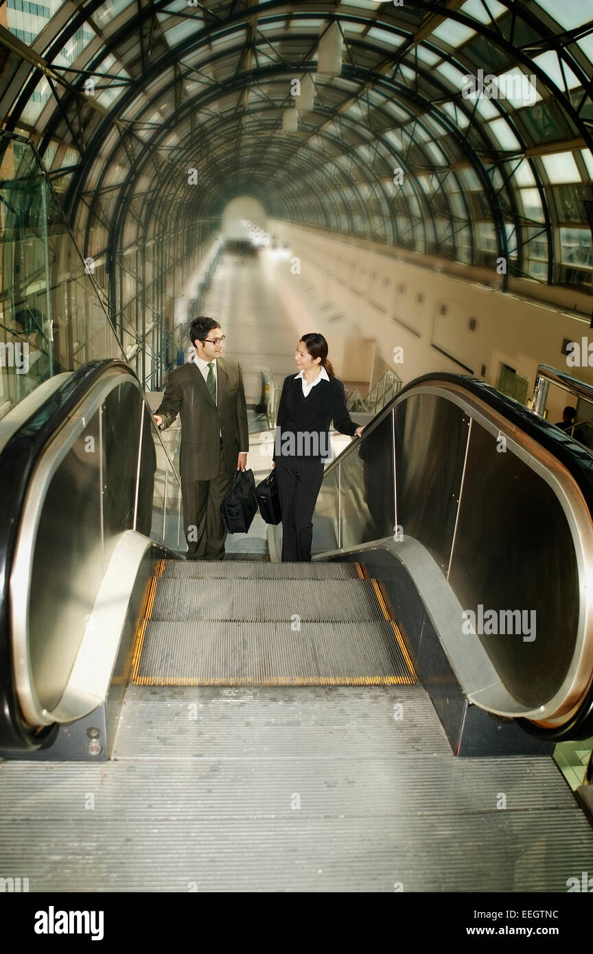 Business couple talking on escalator Stock Photo