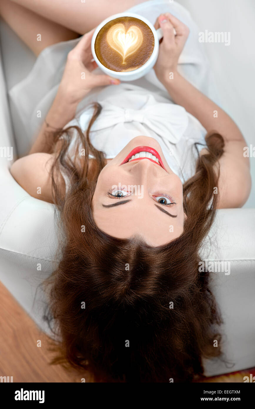 Young woman with coffee cup sitting on the couch at home Stock Photo ...