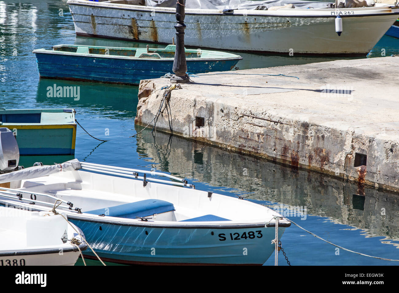 Boats and wall reflection in the water of Spinola Bay which is within St Julians Bay Malta Stock Photo