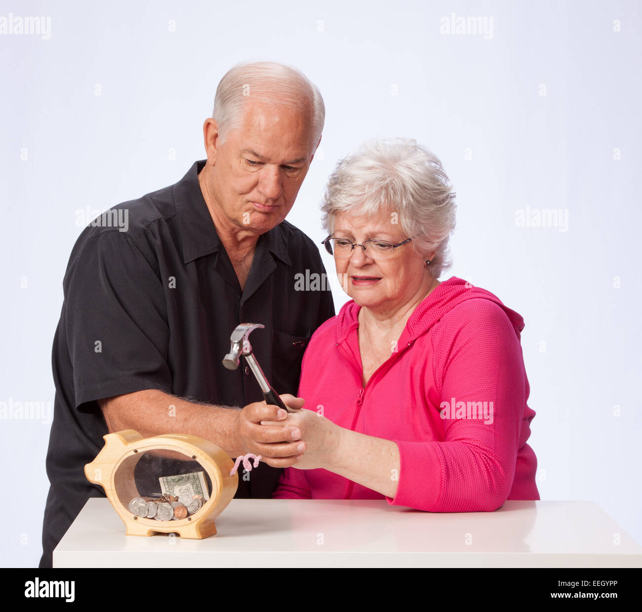 Mature Married Couple Breaking into Piggy Bank Stock Photo - Alamy