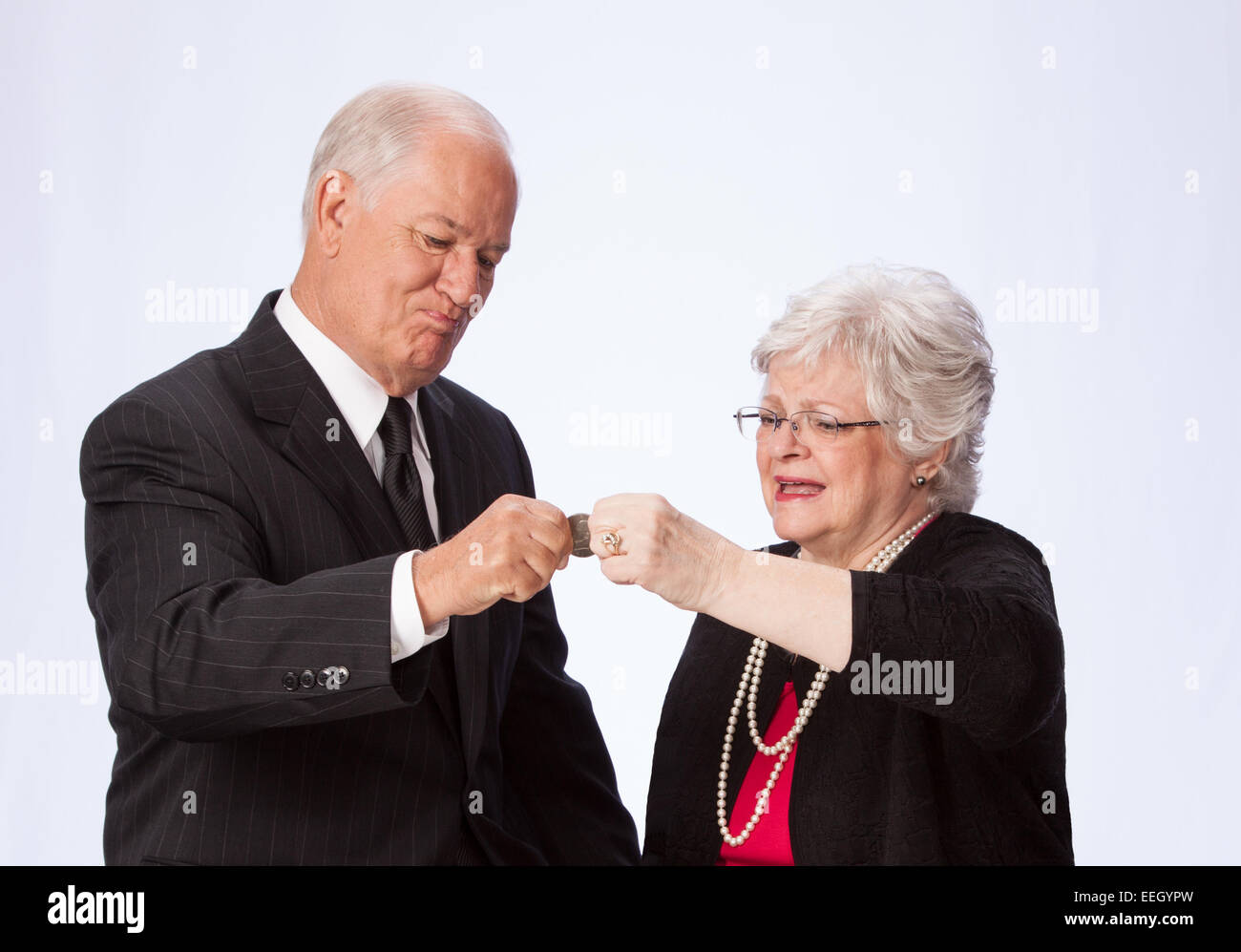 Married Couple Pinching a Penny for Retirement intensely pinching a coin Stock Photo