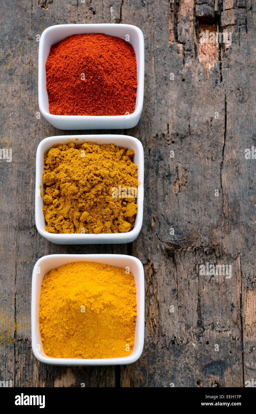 Hot red chili powder, curry and turmeric powder on wooden background