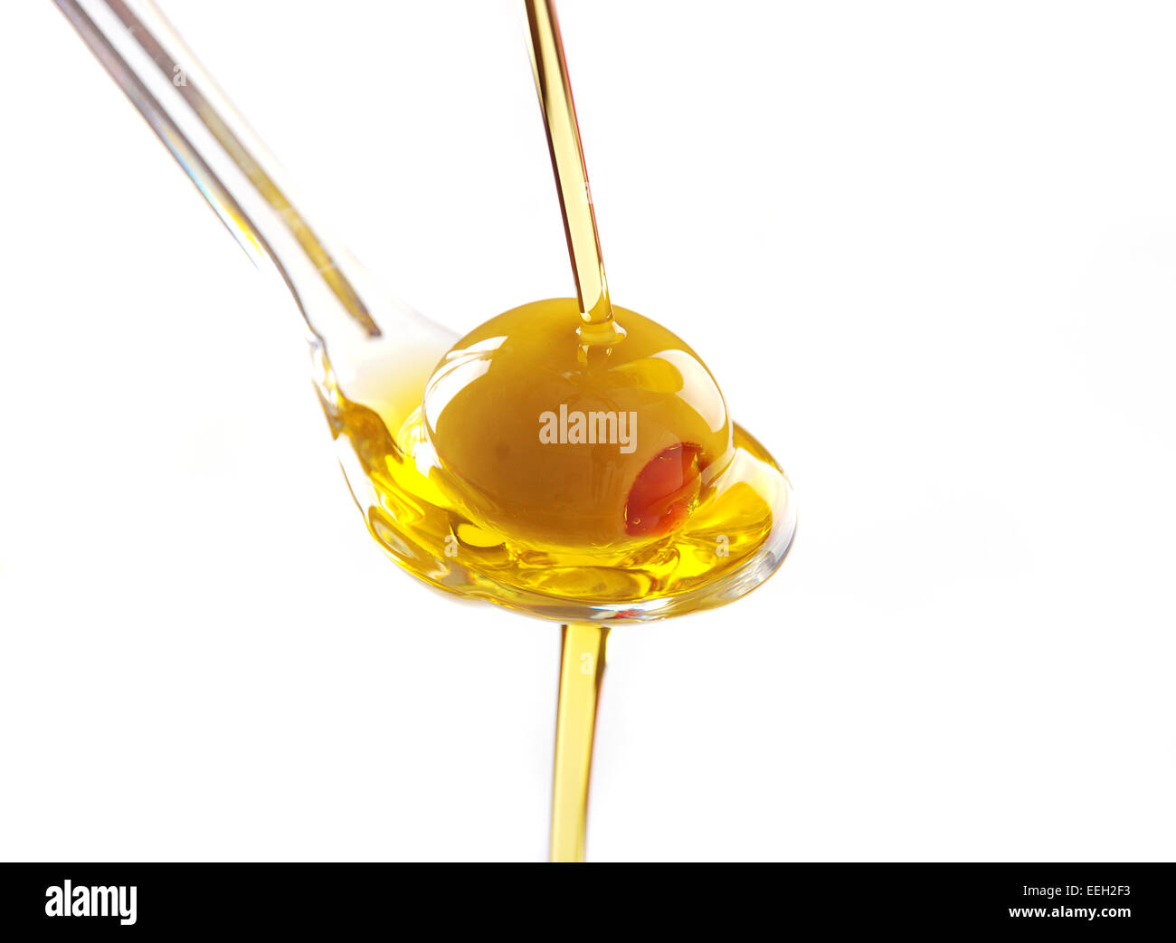 A spoon with an olive under a fall of oil Stock Photo - Alamy