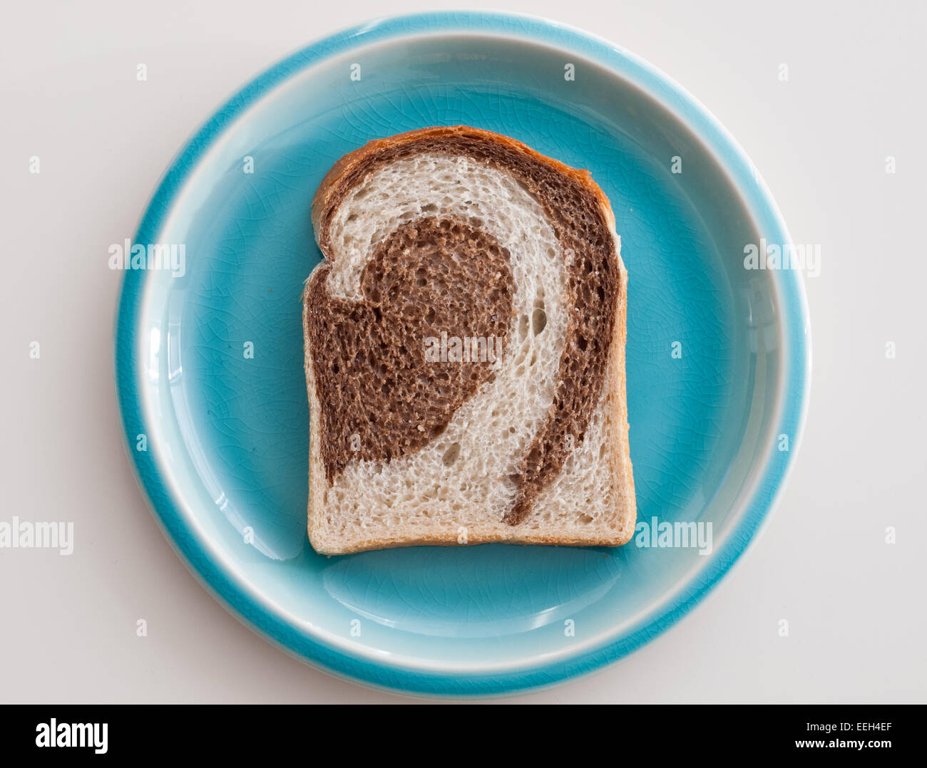 A slice of marble rye bread on a blue plate. Stock Photo