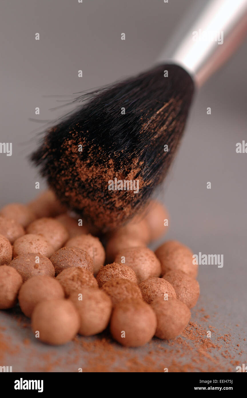 Close up of cosmetic bronzing powder / foundation beads and cosmetic brush. Stock Photo