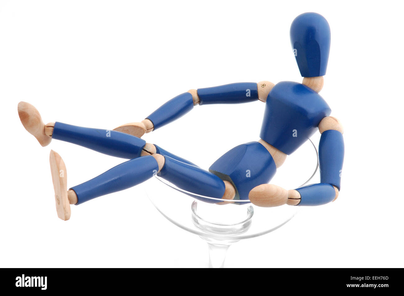 Wooden mannequin female figure reclined in champagne glass. Stock Photo