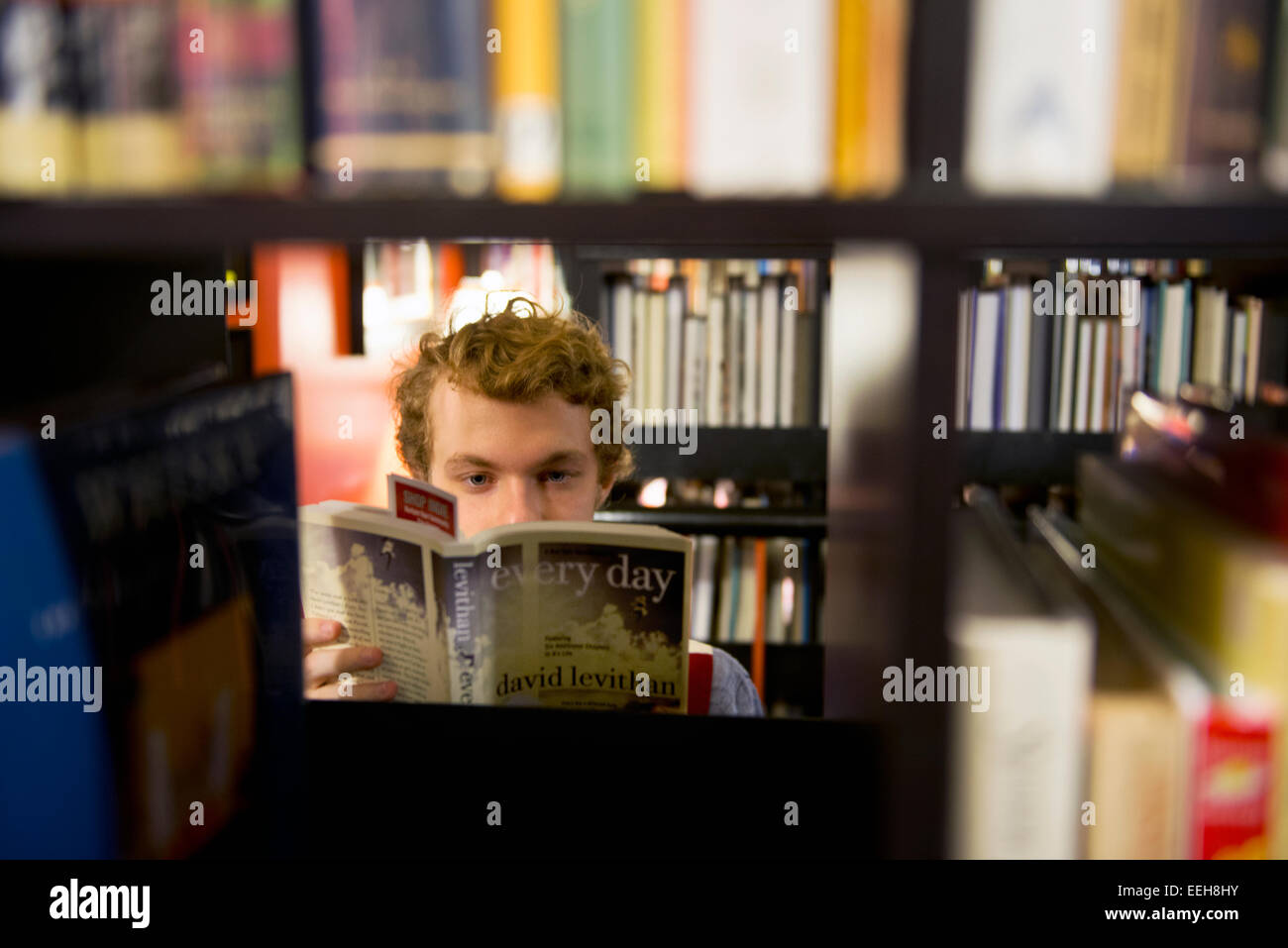 Young man reading a David Levithan book in a public library Stock Photo