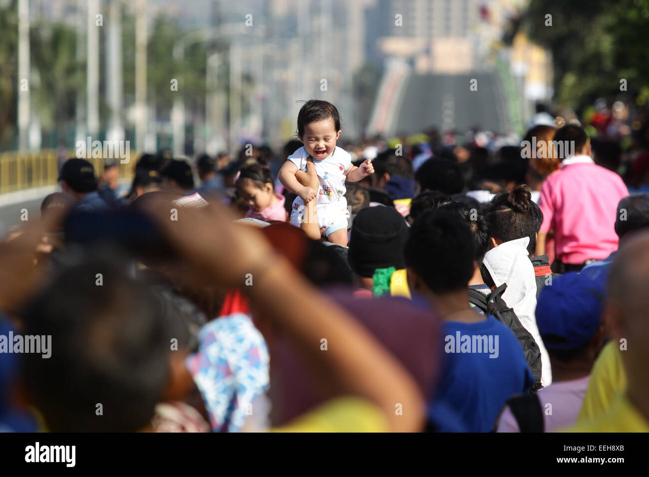 Baclaran, Philippines. 19th Jan, 2015. A baby is raised up while waiting for the Pope's motorcade to the Villamor Airbase in Baclaran, Paranaque on Monday, January 19, 2015. Pope Francis is on his way back to the Vatican after a 5-day visit to the Philippines. Credit:  Mark Fredesjed Cristino/Alamy Live News Stock Photo