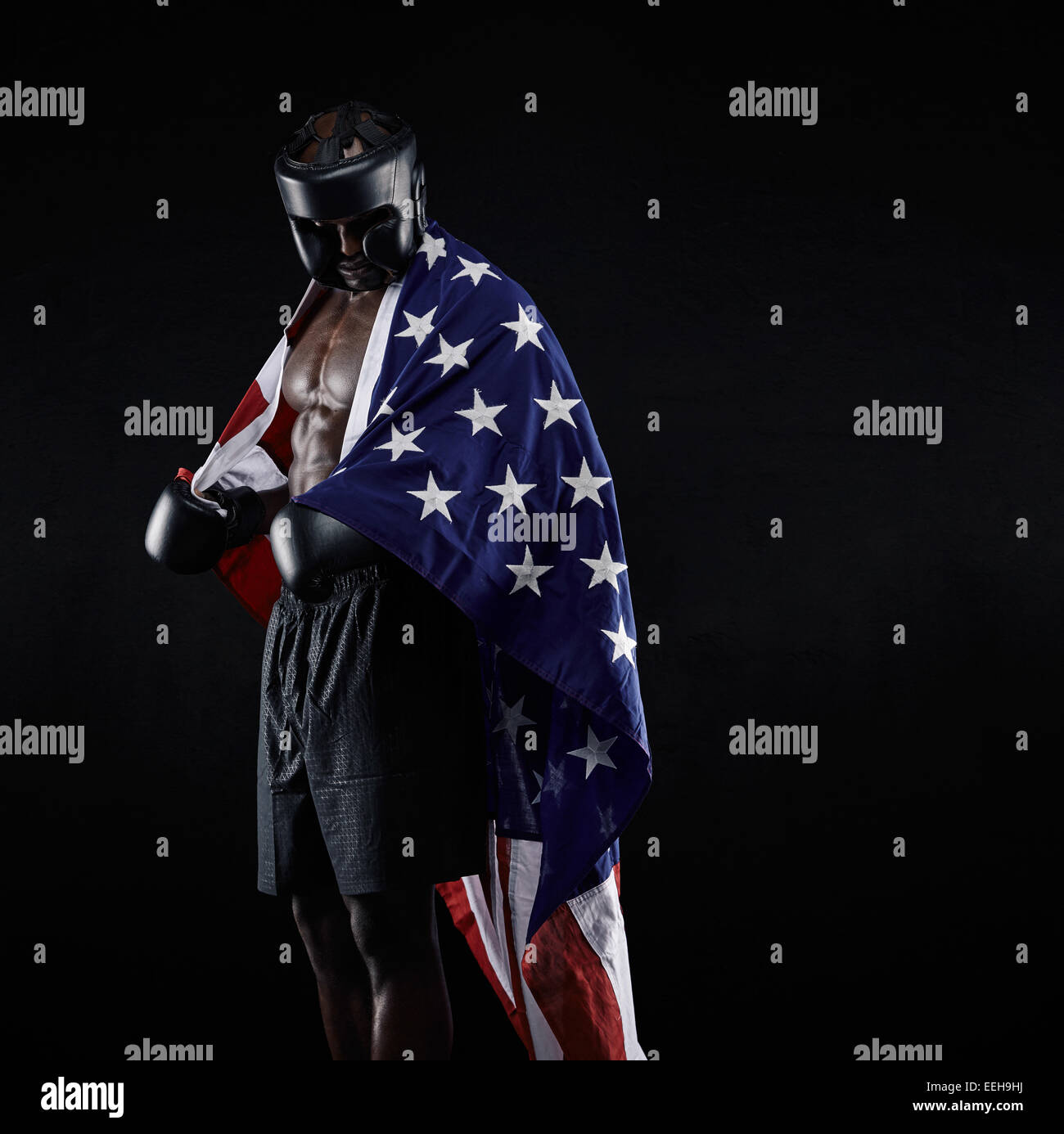 Portrait of african american Boxer with the American flag draped around his body against black background Stock Photo