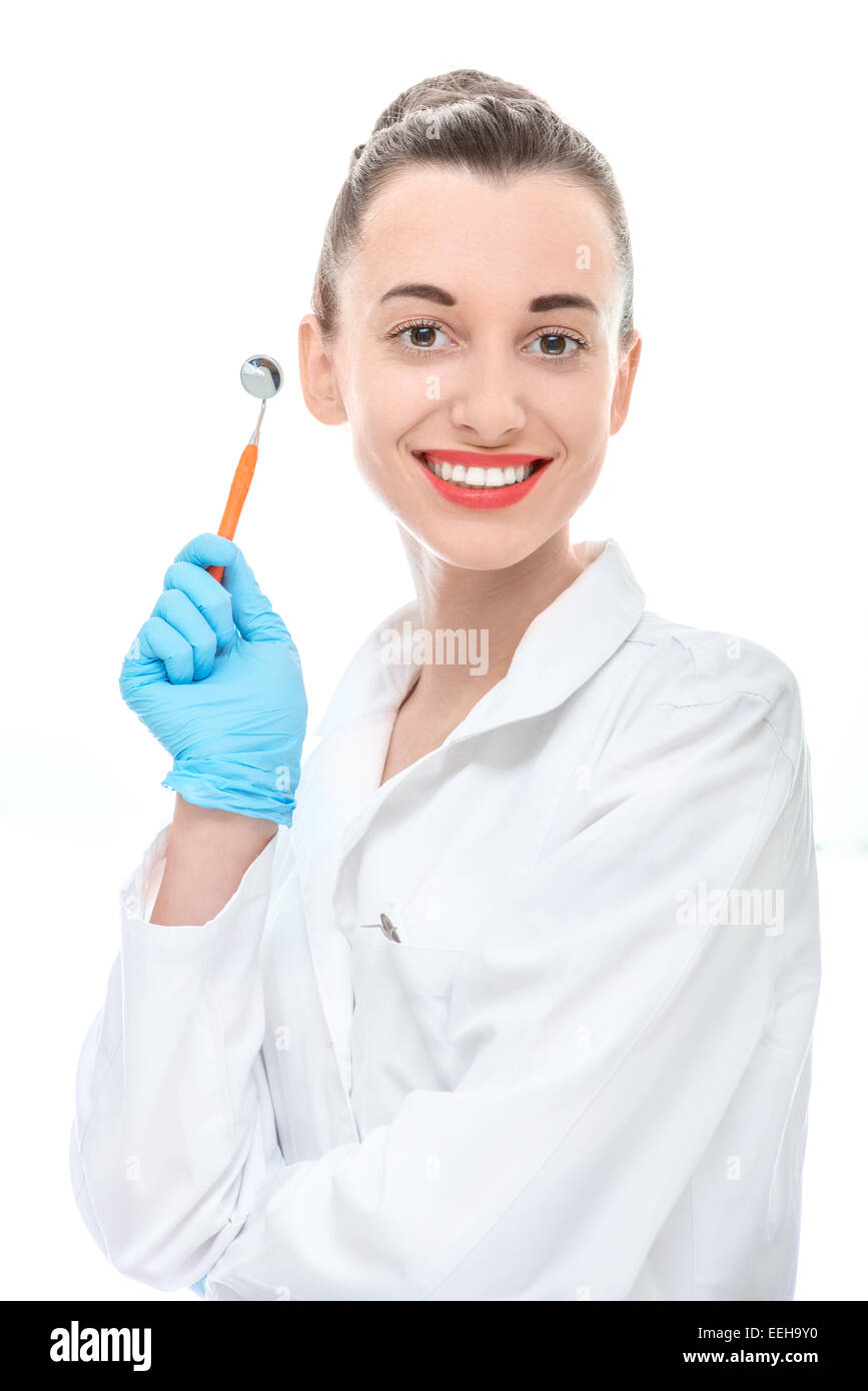 Young woman doctor holding dental mirror and looking at camera on white