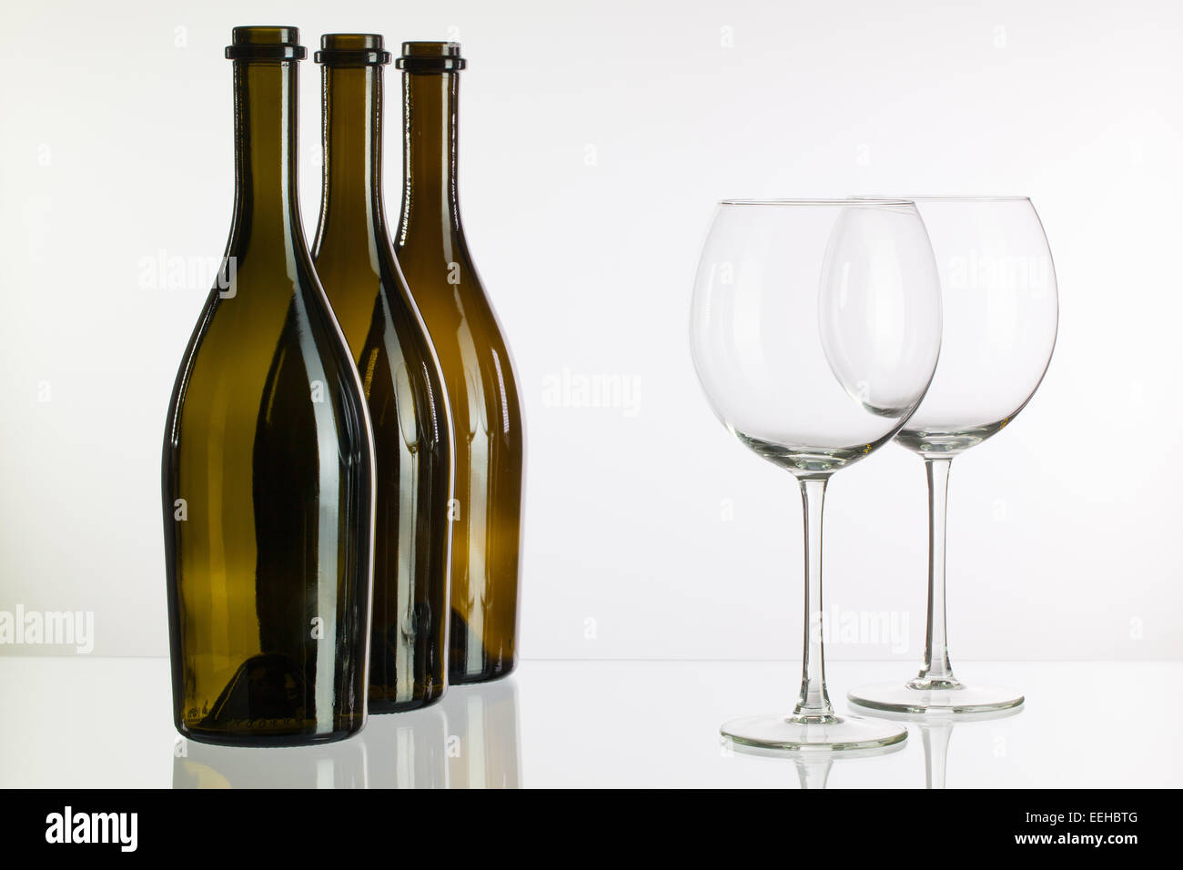 Three empty bottles of wine on a glass table Stock Photo