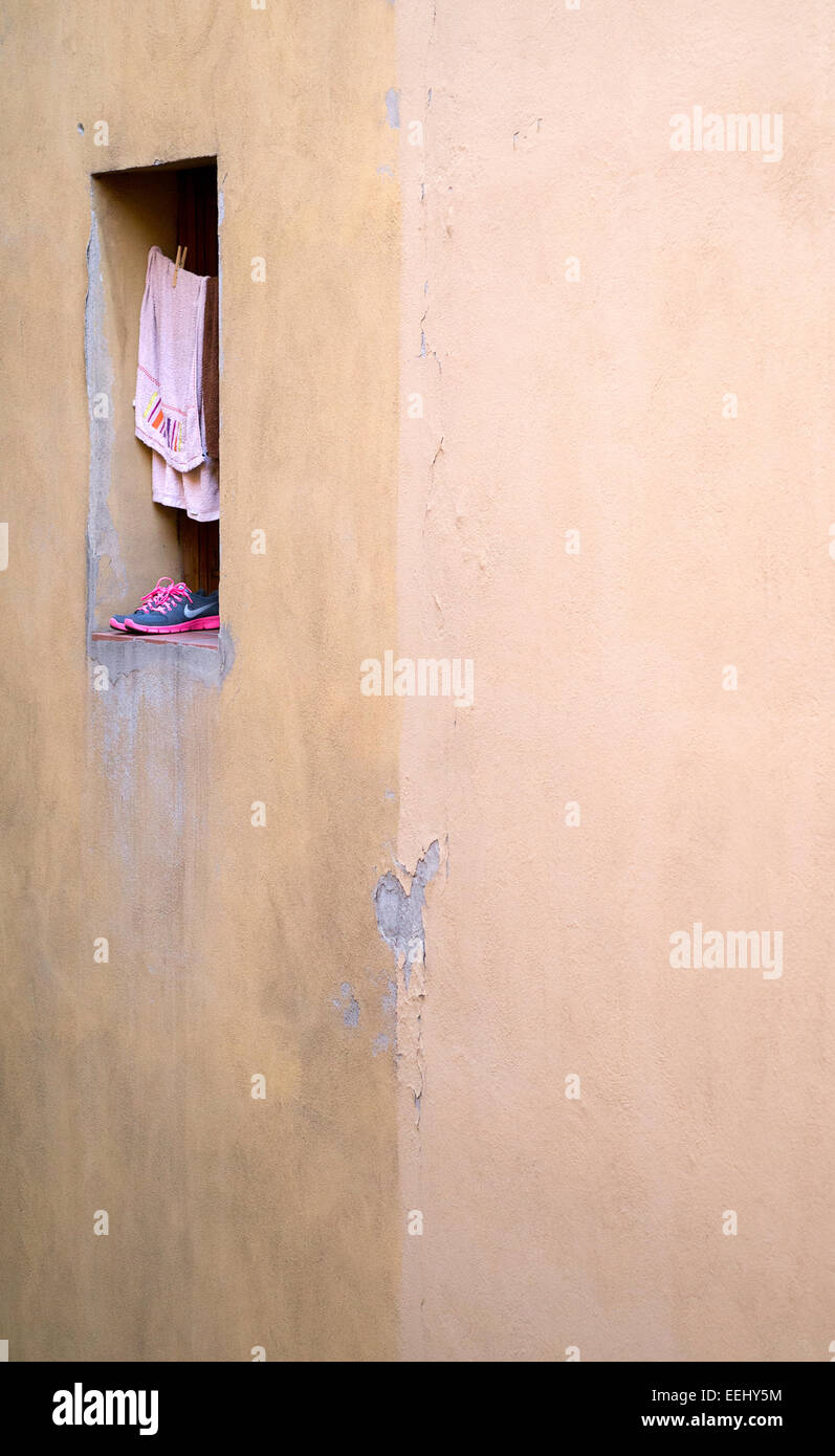 Clothing (pink towel and Nike trainers) drying in a window in a side street of Bologna ,Italy. Stock Photo
