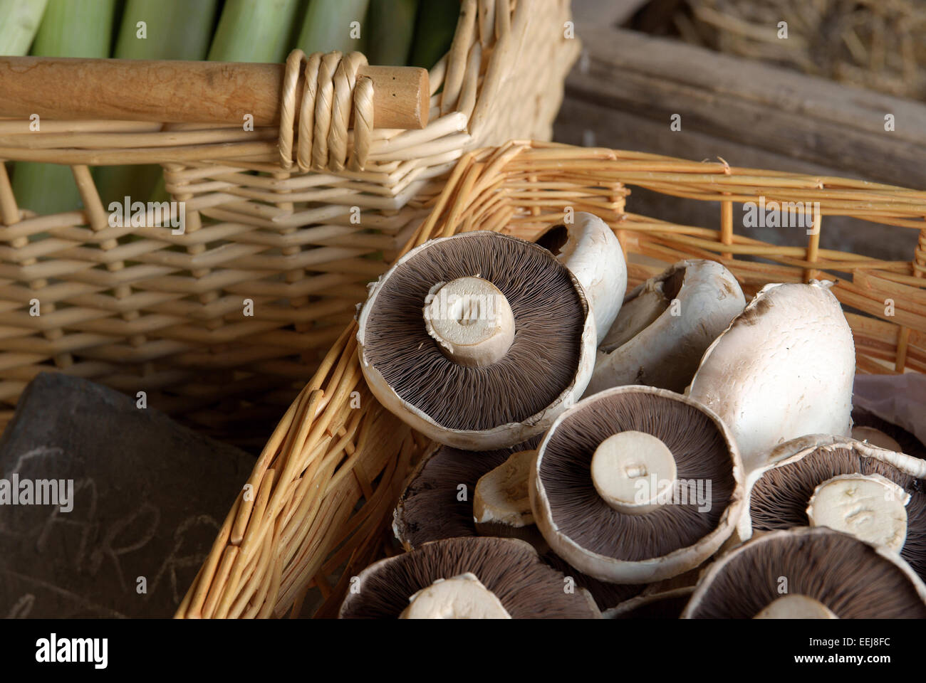 Fresh mushrooms and vegetables on sale in wicker baskets at a rural farm shop Stock Photo