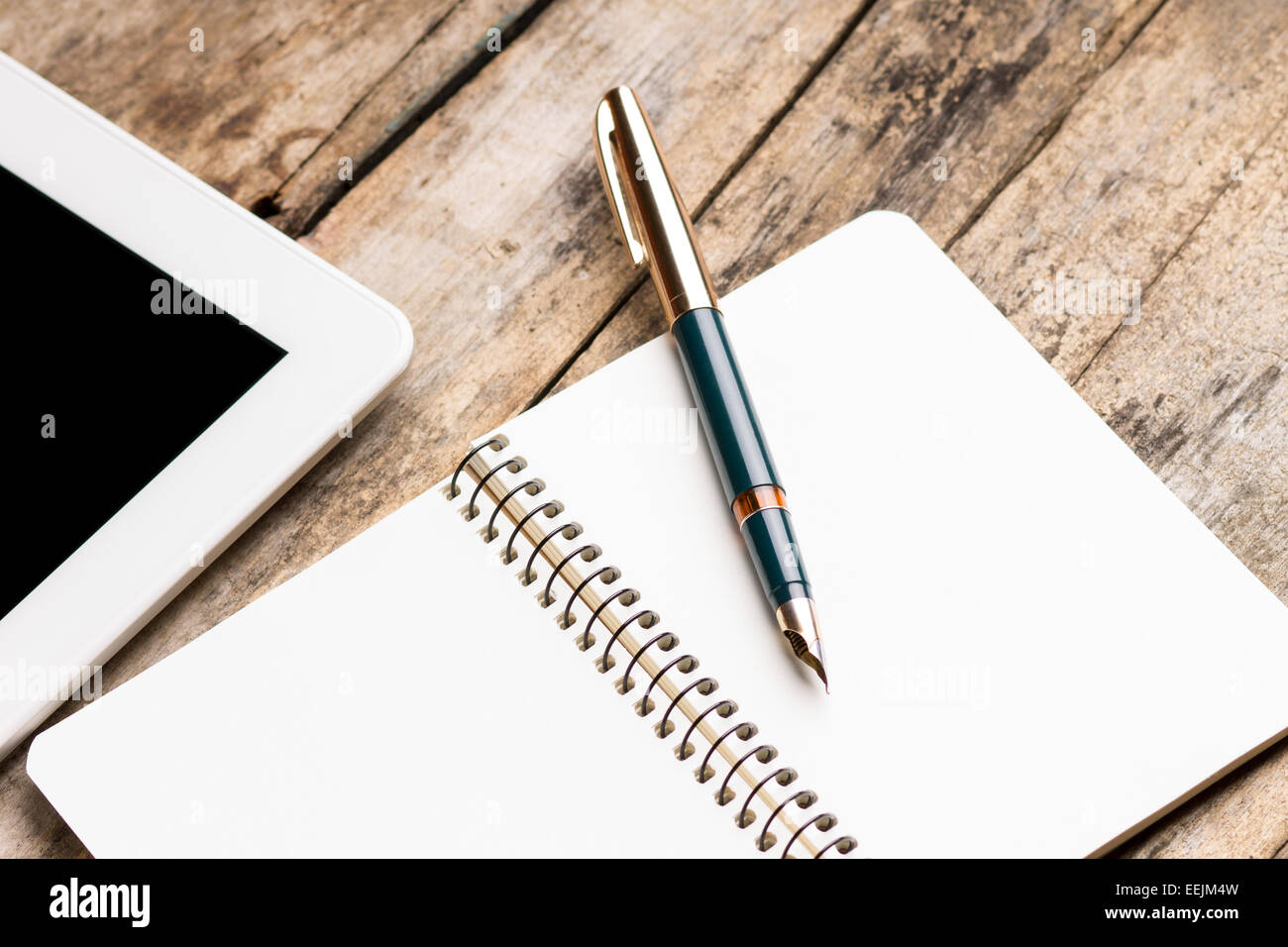 Freelance workplace. Digital tablet with empty notebook and old fountain pen on rustic wooden table. Stock Photo