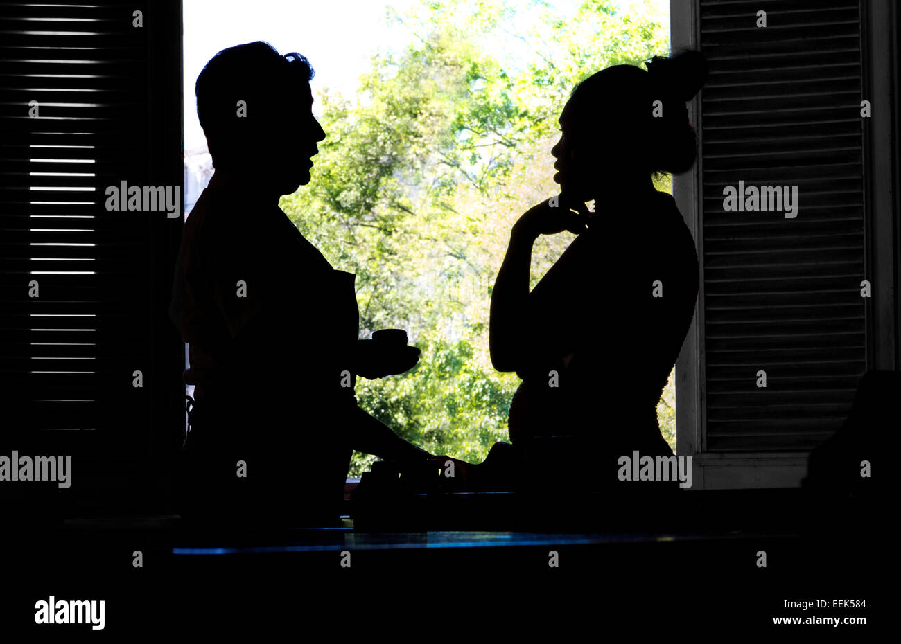 Two women in silhouette talking in front of a café window, Havana, Cuba. Stock Photo