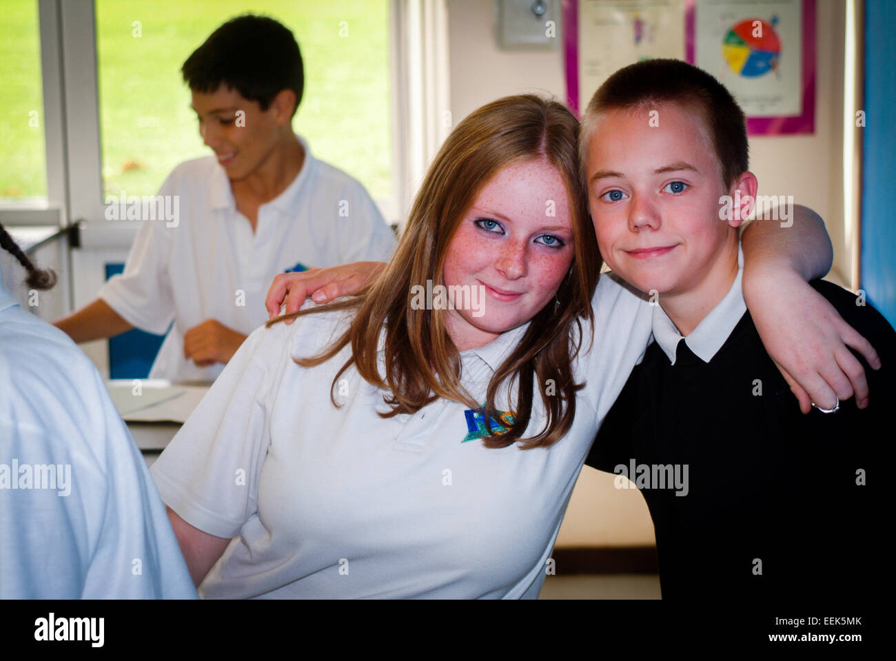 teen boy and girl with arms round in secondary school,UK Stock Photo