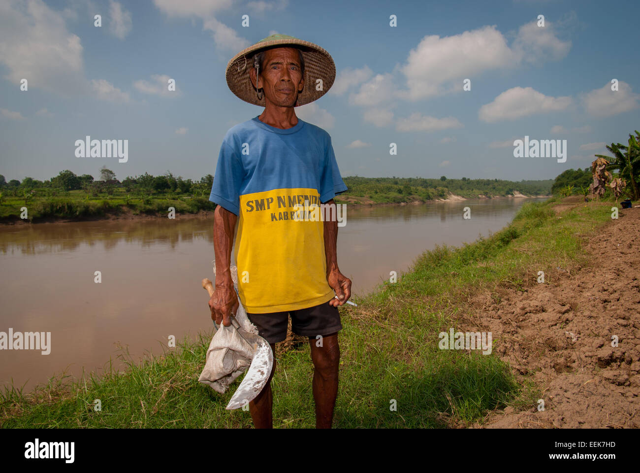 Portrait of a farmer holding a hand sickle on the bank of Bengawan Solo river in Blora, Central Java, Indonesia. Stock Photo