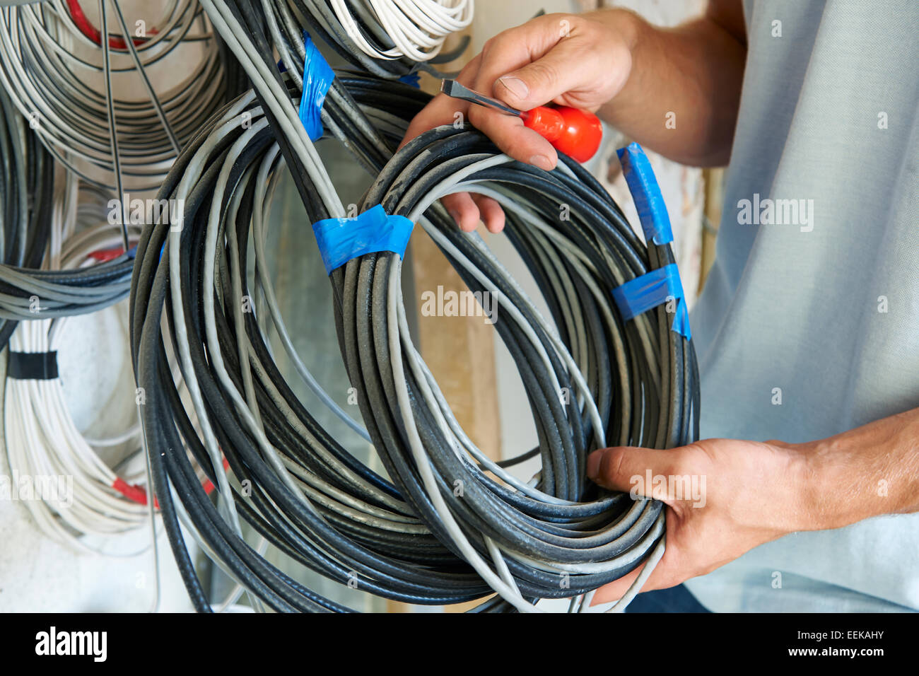 Close Up Of Electrician Fitting Wiring On Construction Site Stock