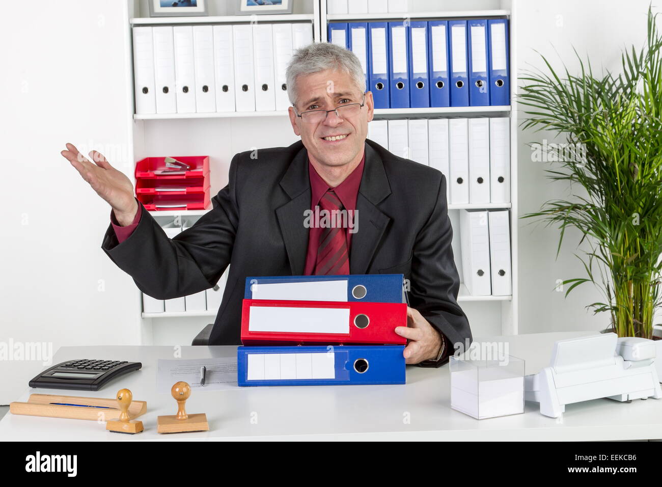 Mann mittleren Alters sitzt im Büro und gestikuliert, Middle-aged man, sitting in his office, gesticulating Stock Photo