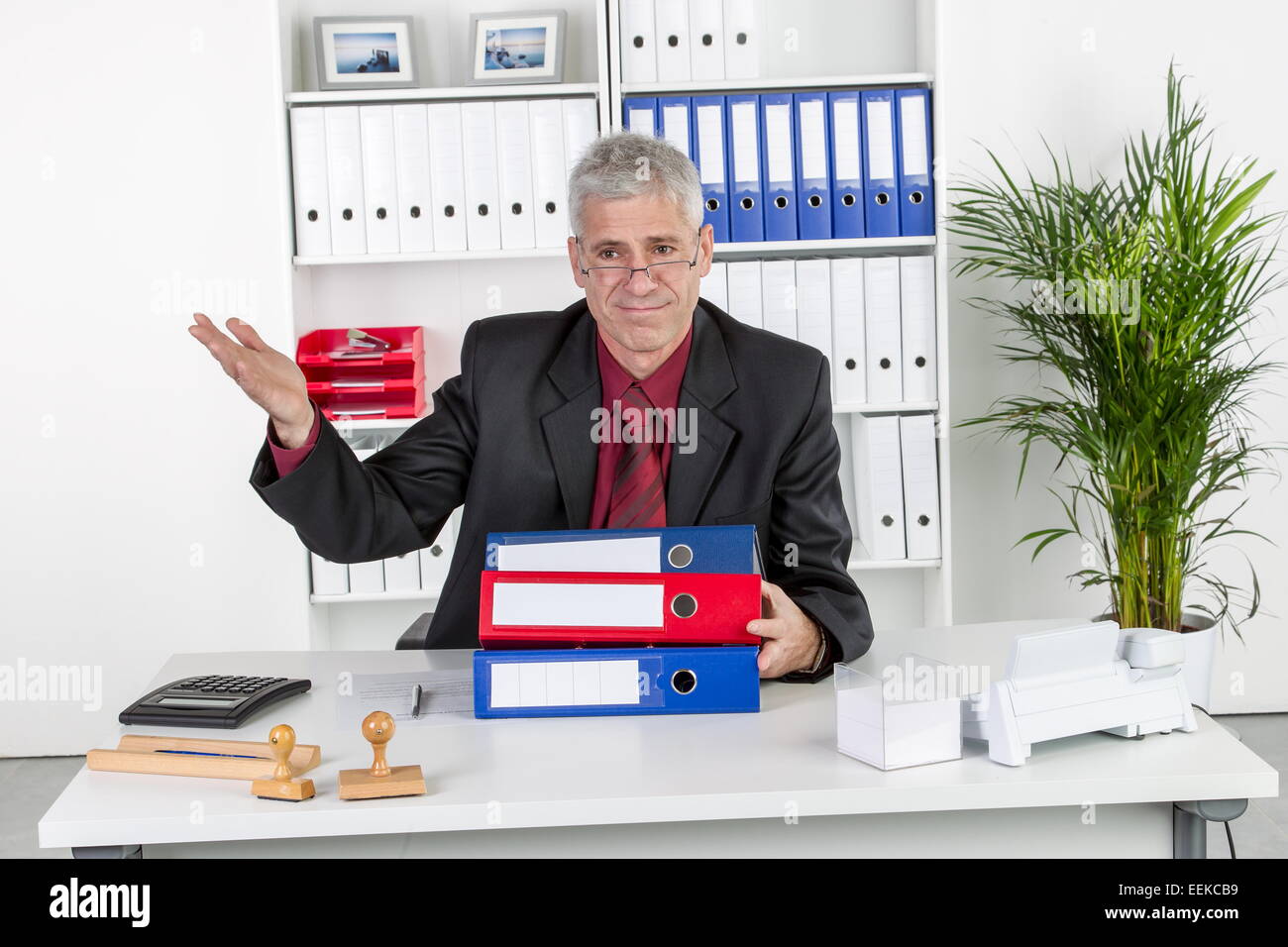 Mann mittleren Alters sitzt im Büro und gestikuliert, Middle-aged man, sitting in his office, gesticulating Stock Photo