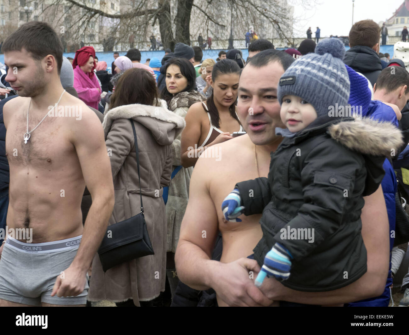 A man who is going to bathe in the river, holding his little boy in winter clothes. 19th Jan, 2015. -- 19 January, 2015, Kiev, Ukraine, great Christian holiday Epiphany. One of the main traditions of celebration is swimming in Jordan (the so-called consecrated priest hole). The current winter was unusually mild in Ukraine and swimming just held on the beach. Ukrainian Church of the Moscow Patriarchate traditionally celebrated in Obolon. © Igor Golovniov/ZUMA Wire/Alamy Live News Stock Photo
