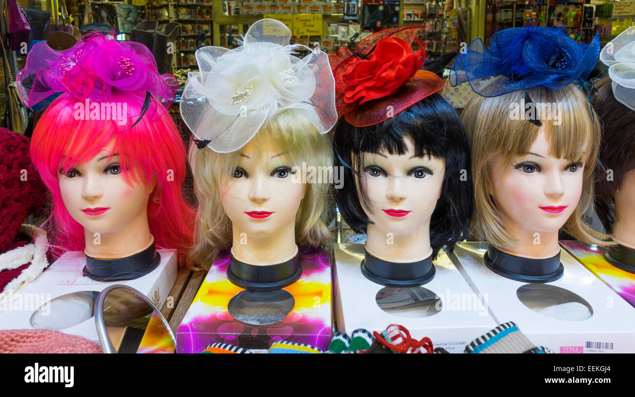Four Manikins heads displaying wigs and hats on an indoor market stall. Stock Photo
