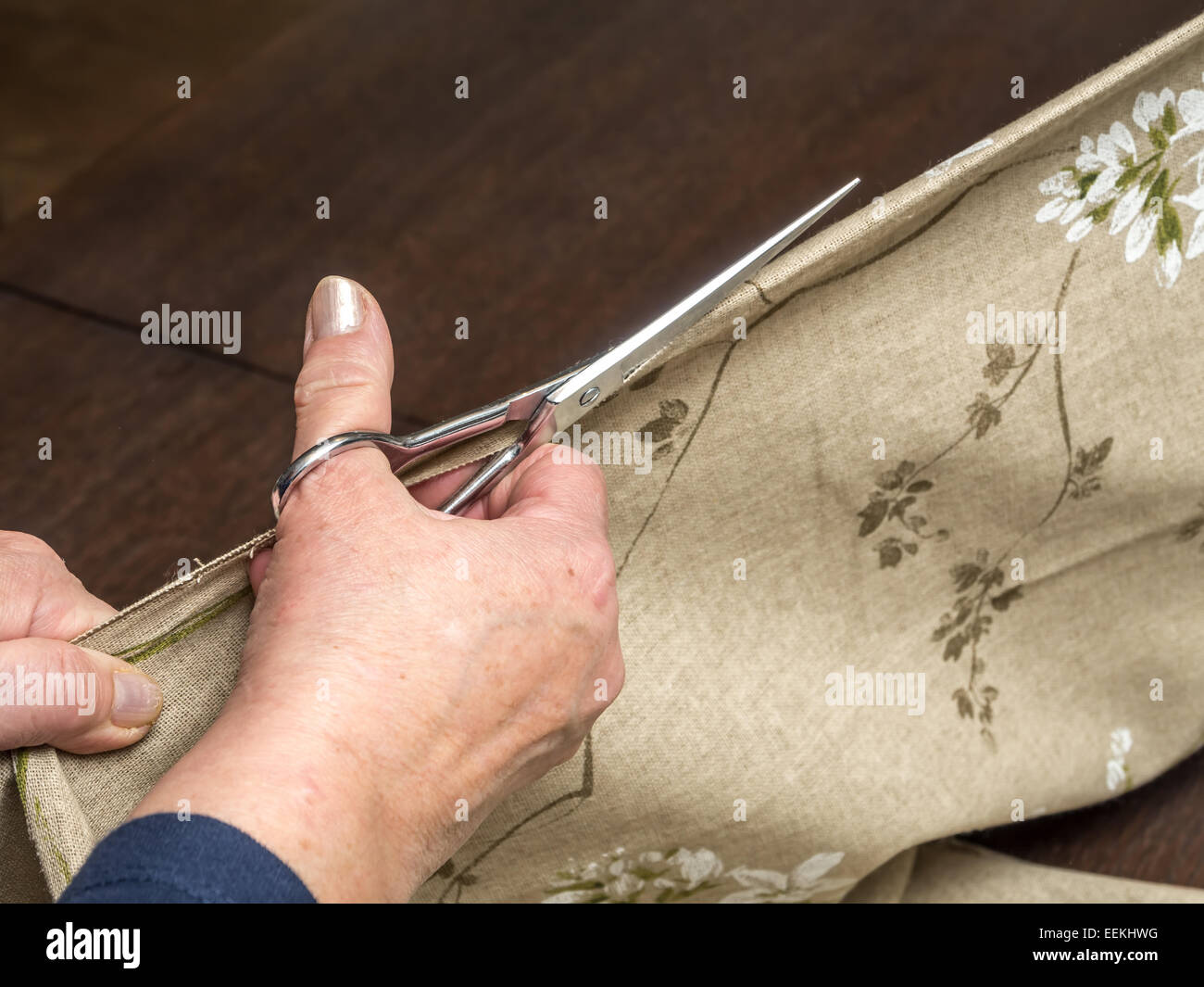 Closeup of senior woman's hands cutting linen in half using scissors Stock Photo