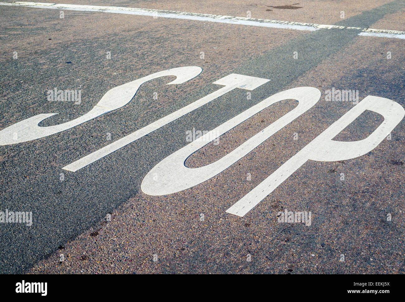 The word STOP painted on an asphalt road. Stock Photo