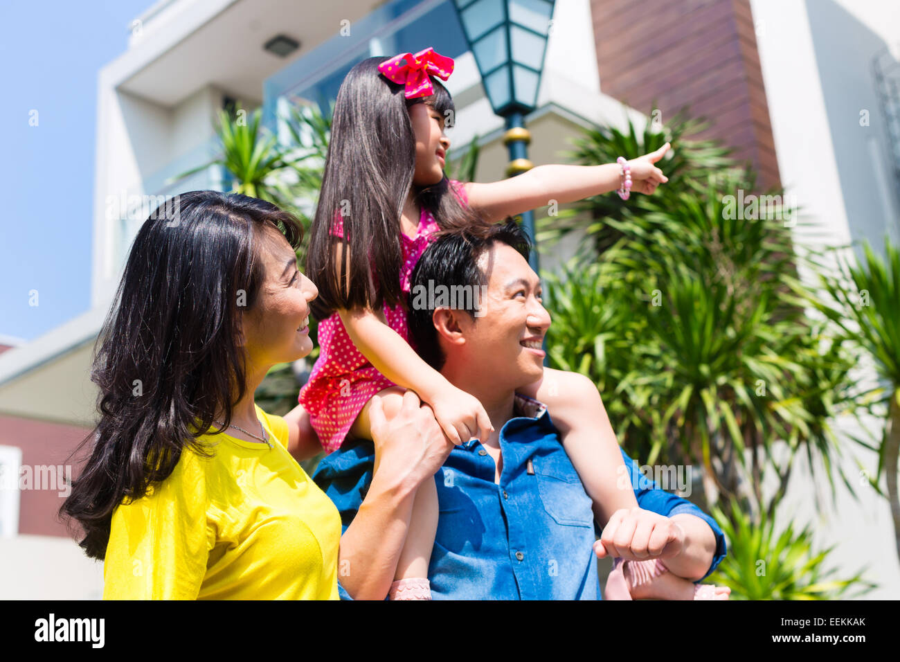 Asian Chinese family of parents and child standing proud in front of  modern home Stock Photo