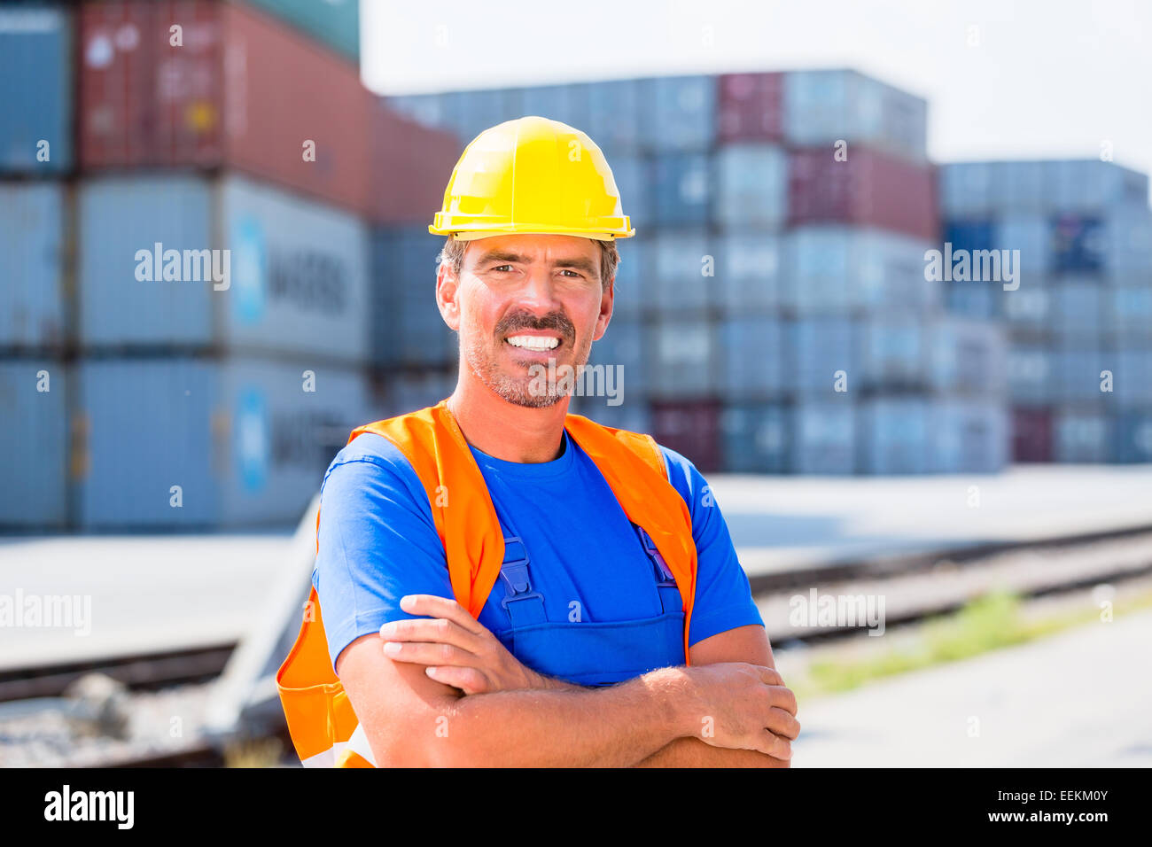 Worker standing in front of row of containers on port or yard of shipment company Stock Photo