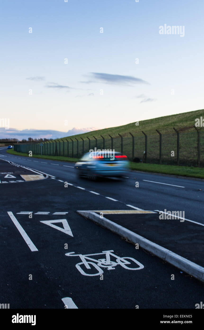 A car traveling at speed past a cycle lane. Ironically cyclists use the road and put themselves in danger rather than use it Stock Photo