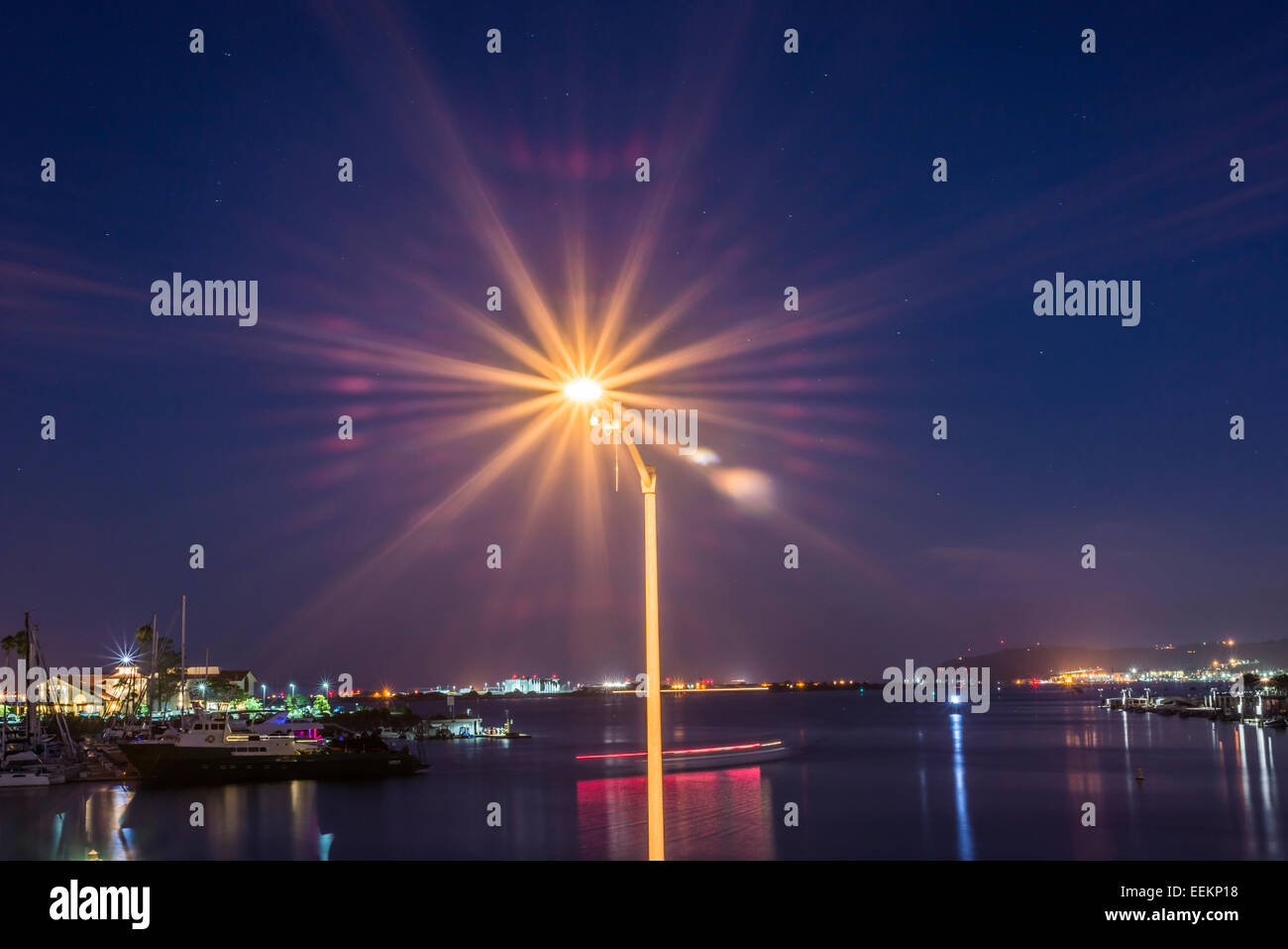 Light post illuminated above San Diego Harbor at night. San Diego