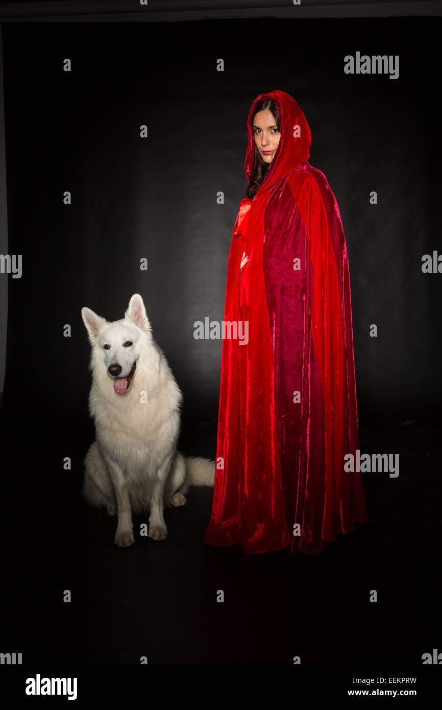 Woman wearing a red hood posing in studio with her dog Stock Photo