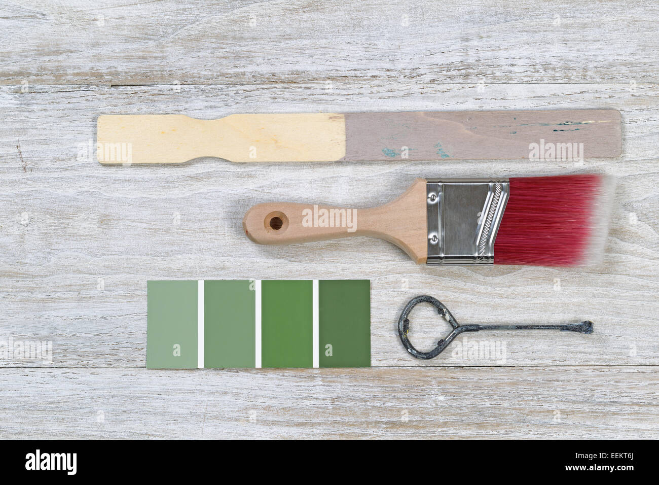 Paint brush with used stick, lid opener, and paint color choice on old white wooden boards Stock Photo
