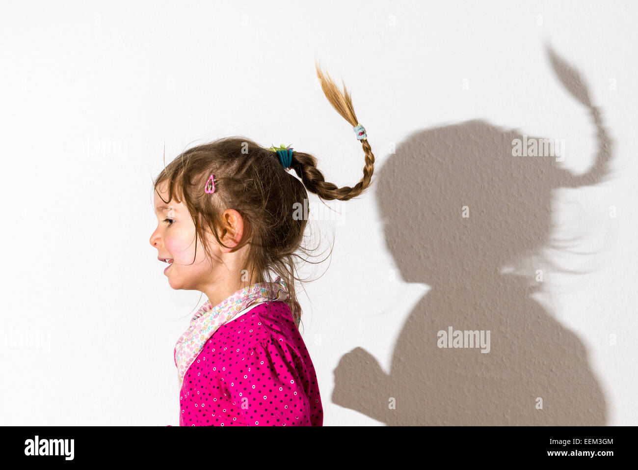 Girl, 3 years, wearing a pink shirt, dancing, casting a shadow on a white  wall Stock Photo - Alamy
