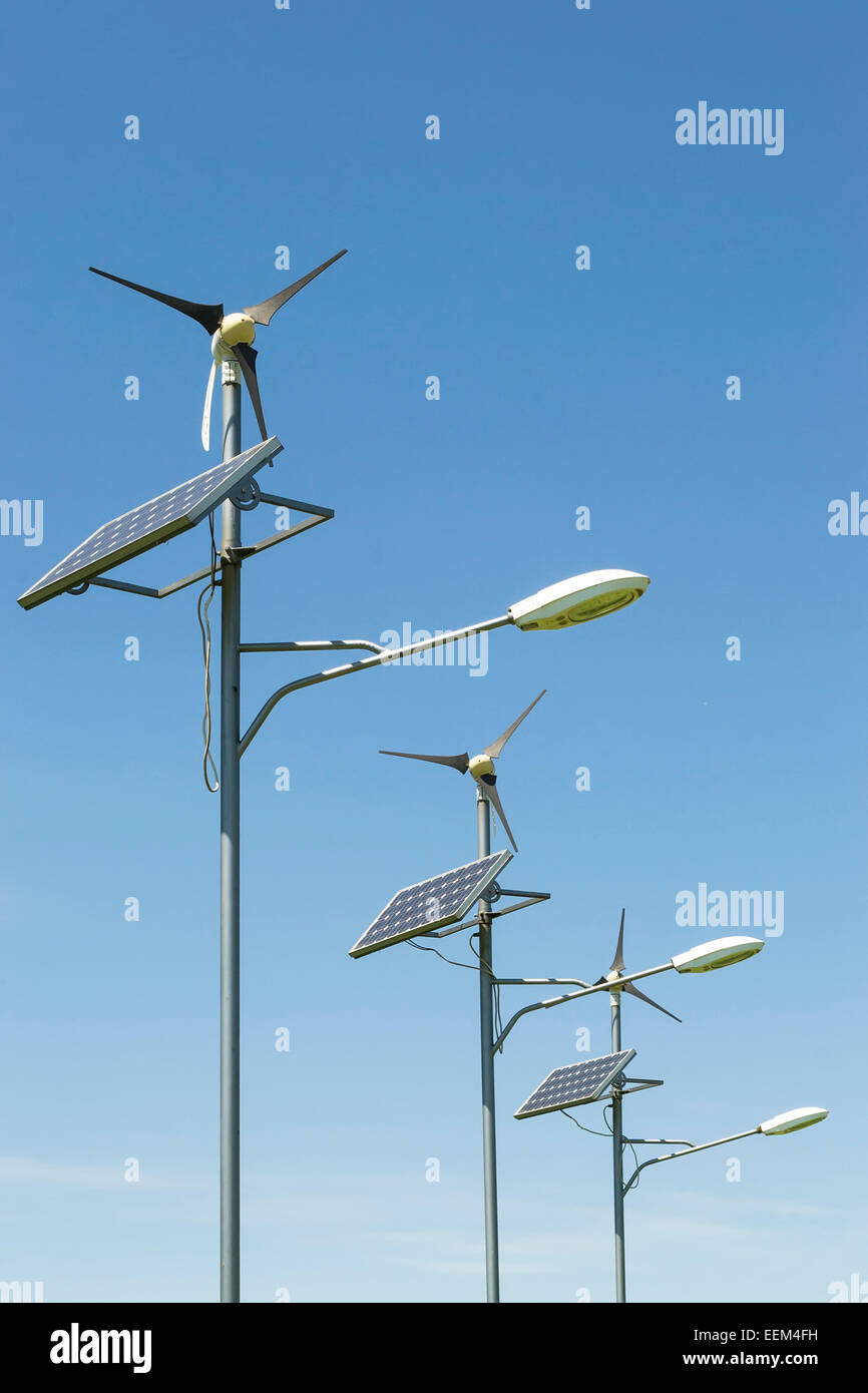 Row of three street lighting poles using alternative energy as power source in the form of a solar panel and small wind turbine Stock Photo
