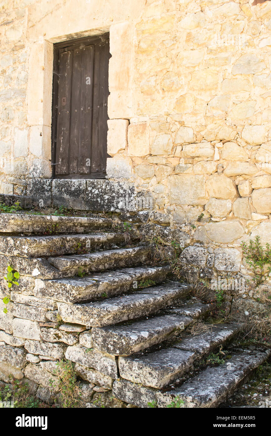 Old stone steps leading towards a wooden closed door Stock Photo