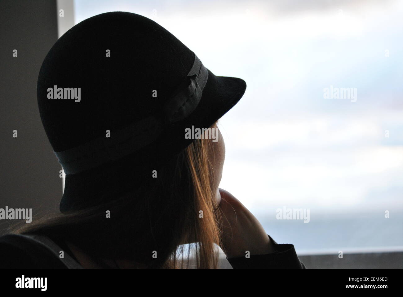 Woman in black hat looking through window Stock Photo - Alamy