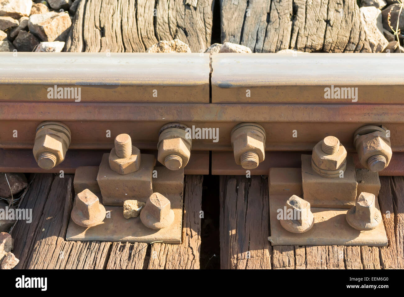 Steel railroad tracks coupling with reinforced bolts and nuts attached to a wooden beam frame Stock Photo
