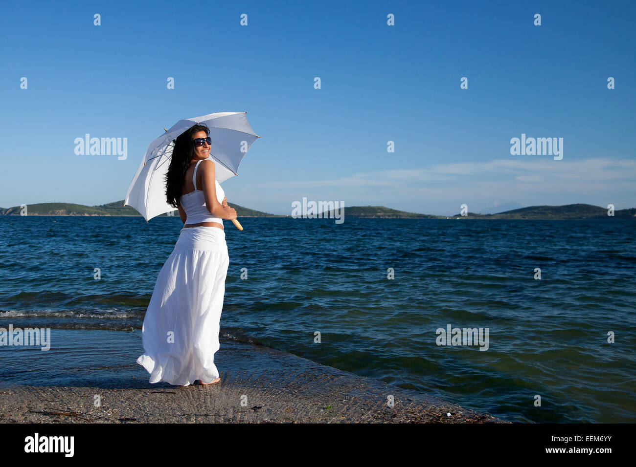 Smiling woman standing by the sea holding a parasol, Greece Stock Photo ...