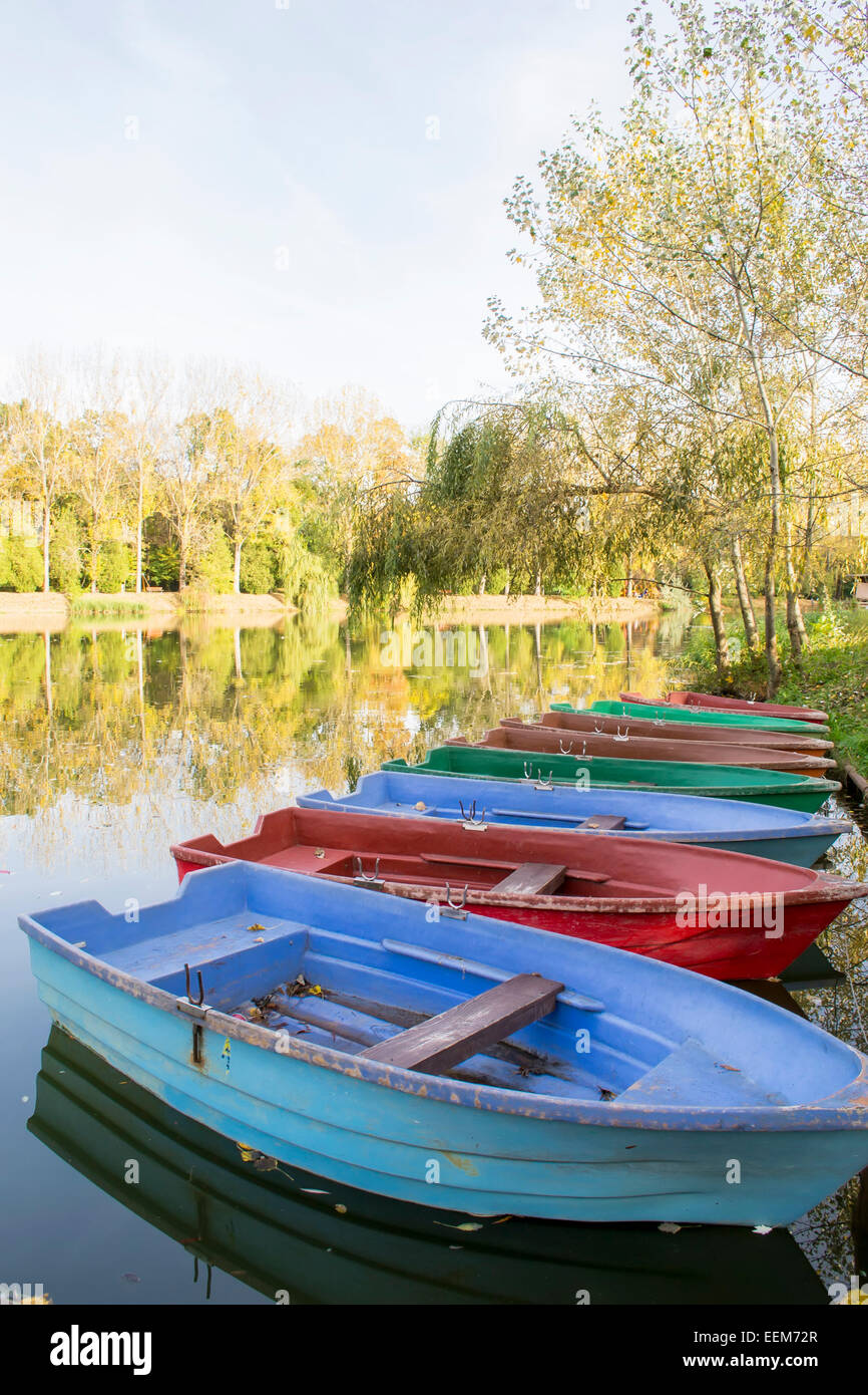 Colored fiberglass recreational boats anchored on the lake shore at the end of the season Stock Photo
