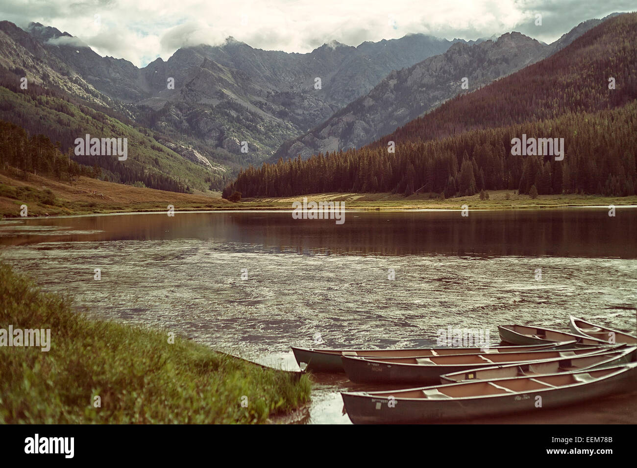 USA, Colorado, Vail, Piney Lake, Empty kayaks next to lakeshore with mountain range on background Stock Photo