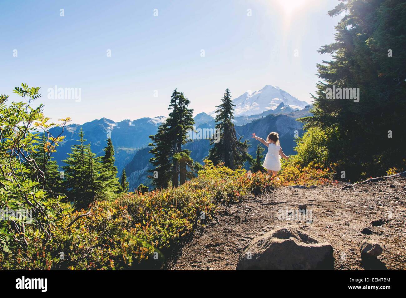 Girl standing on mountain trail with her arm outstretched, USA Stock Photo