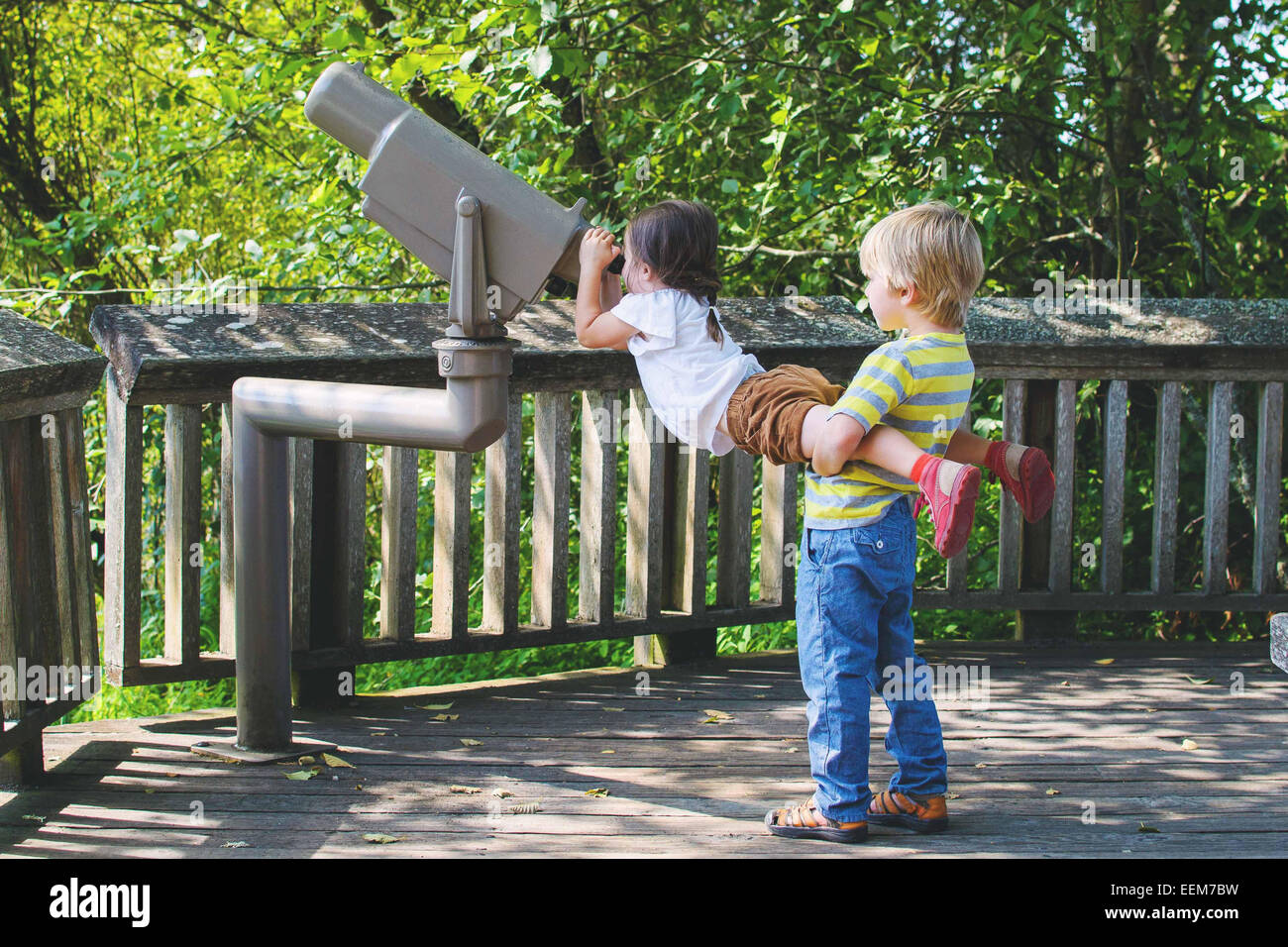 Young boy (4-5) helping girl (2-3) looking through telescope Stock Photo