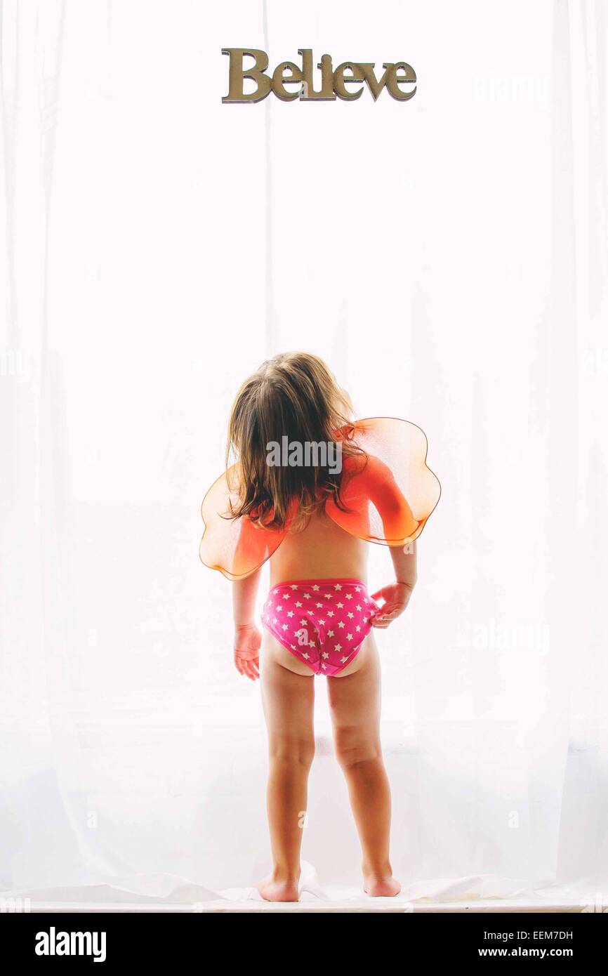 Rear view of a girl with fairy wings looking at believe sign Stock Photo
