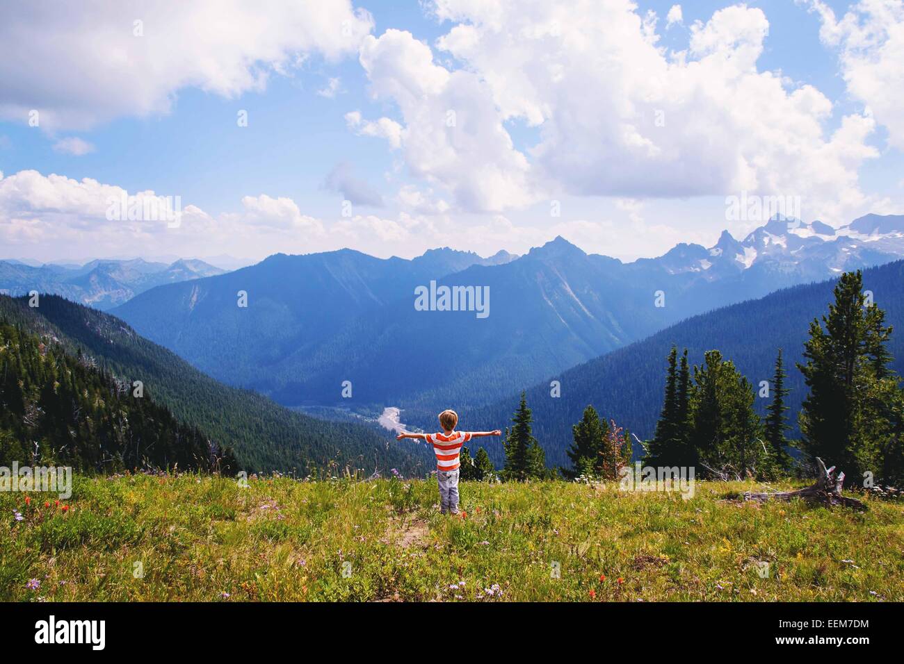 Boy standing in mountains with his arms outstretched Stock Photo