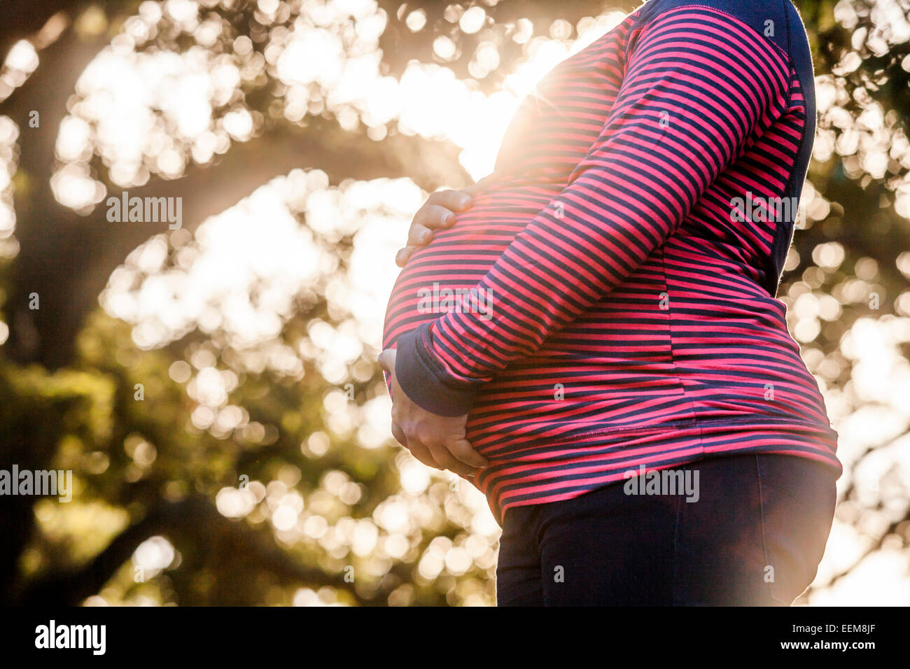 Pregnant Caucasian mother holding her stomach outdoors Stock Photo - Alamy
